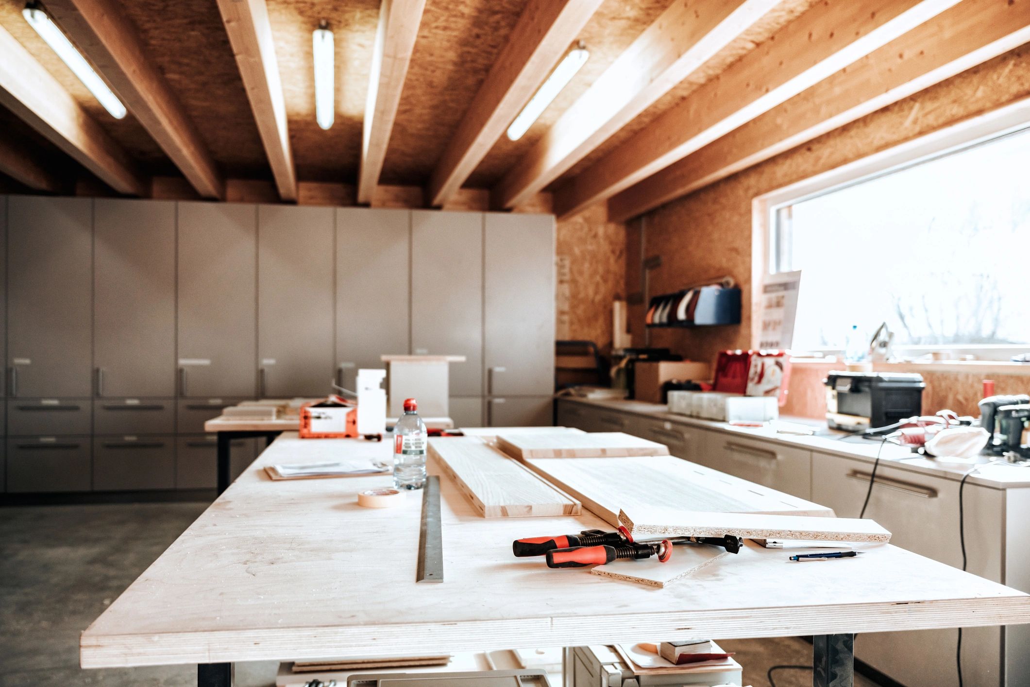 workbench with wooden planks and tools in carpentry manufacturing hall