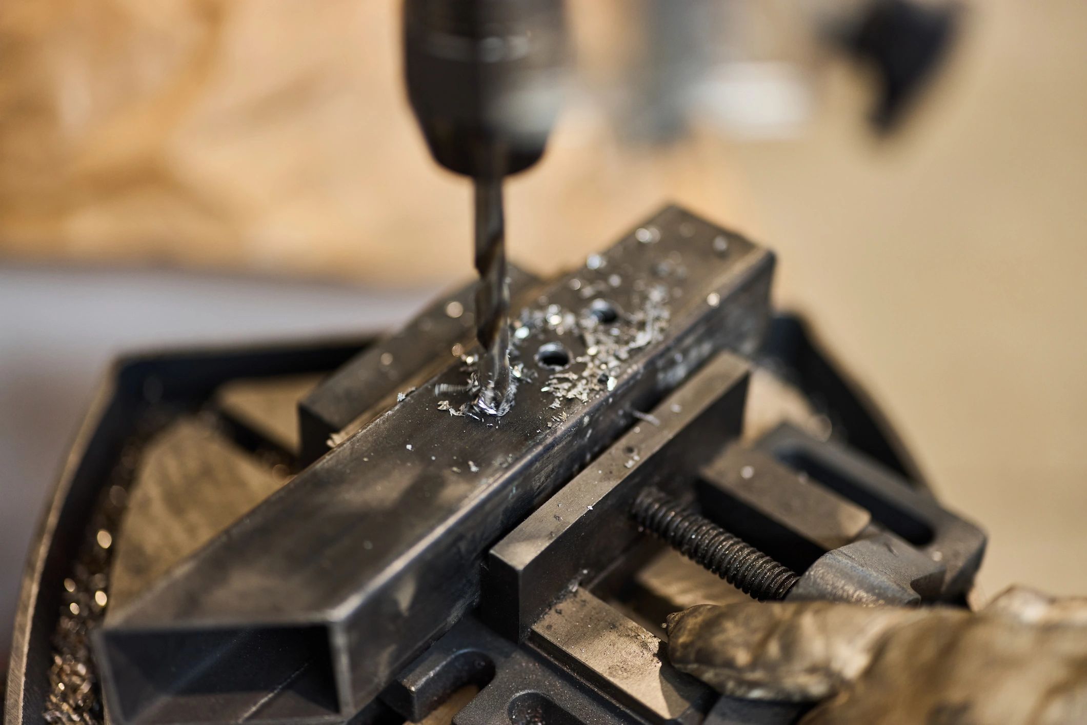 Drilling into a metal piece in a workshop setup with detailed view.
